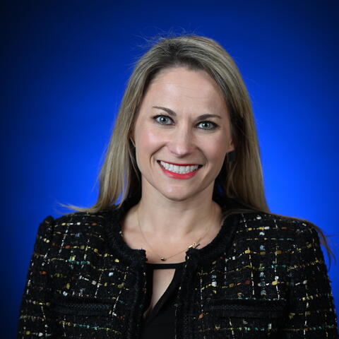 A woman with blonde hair in front of a blue background
